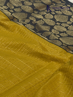 Mustard yellow art silk saree with navy blue floral zari border and textured weave displayed on white background Kadamparii SIlk