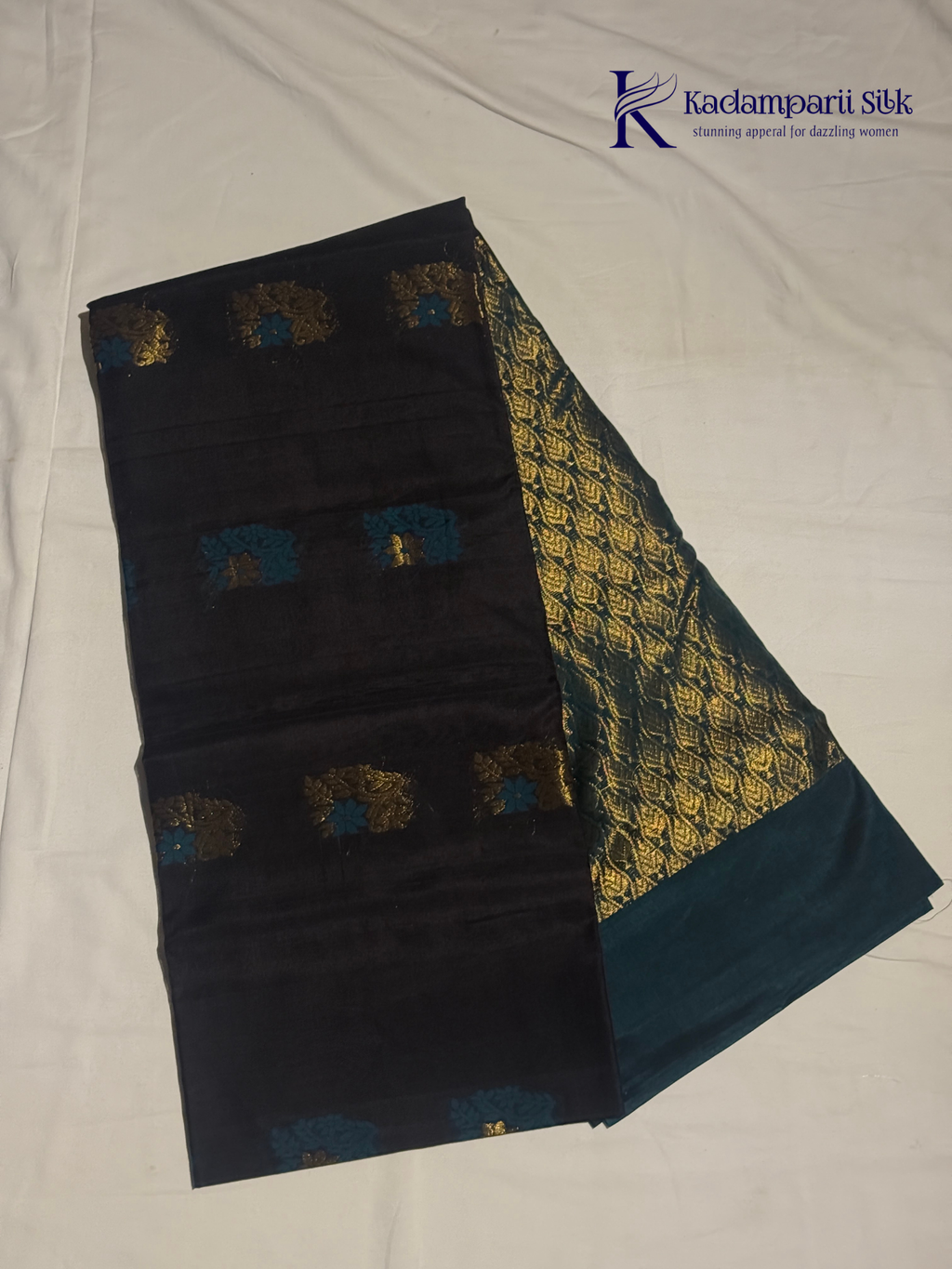 Black saree with gold and blue patterns on a white background, branded 'Kadamparii Silk'. Silk Cotton
