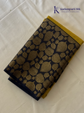 Mustard yellow art silk saree with navy blue floral zari border and textured weave displayed on white background Kadamparii SIlk